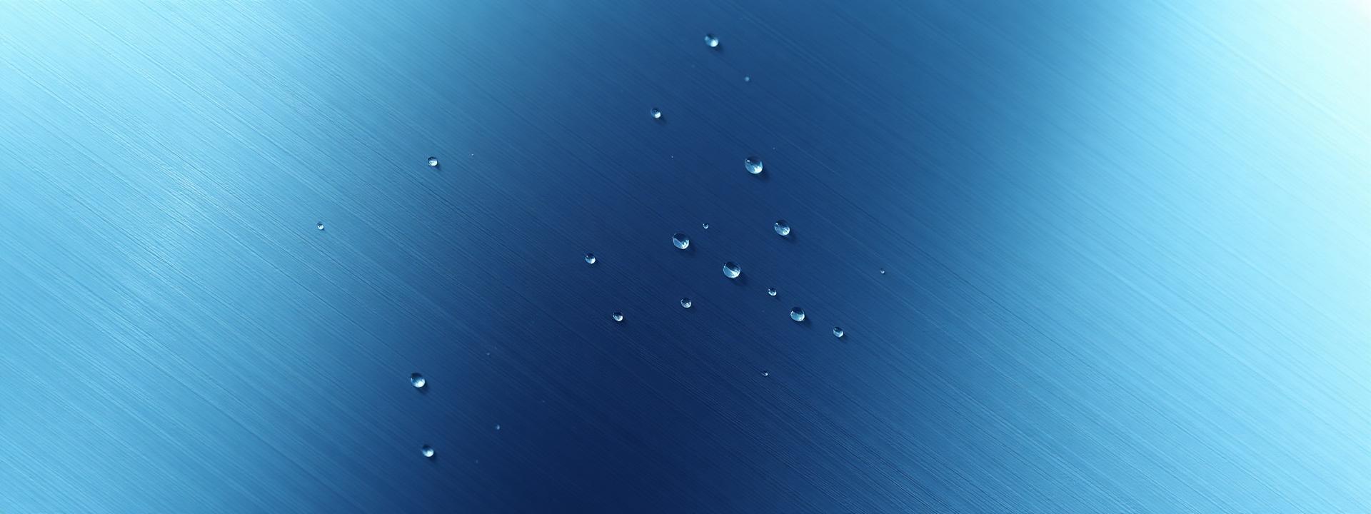 Close-up of a brushed steel surface with water droplets